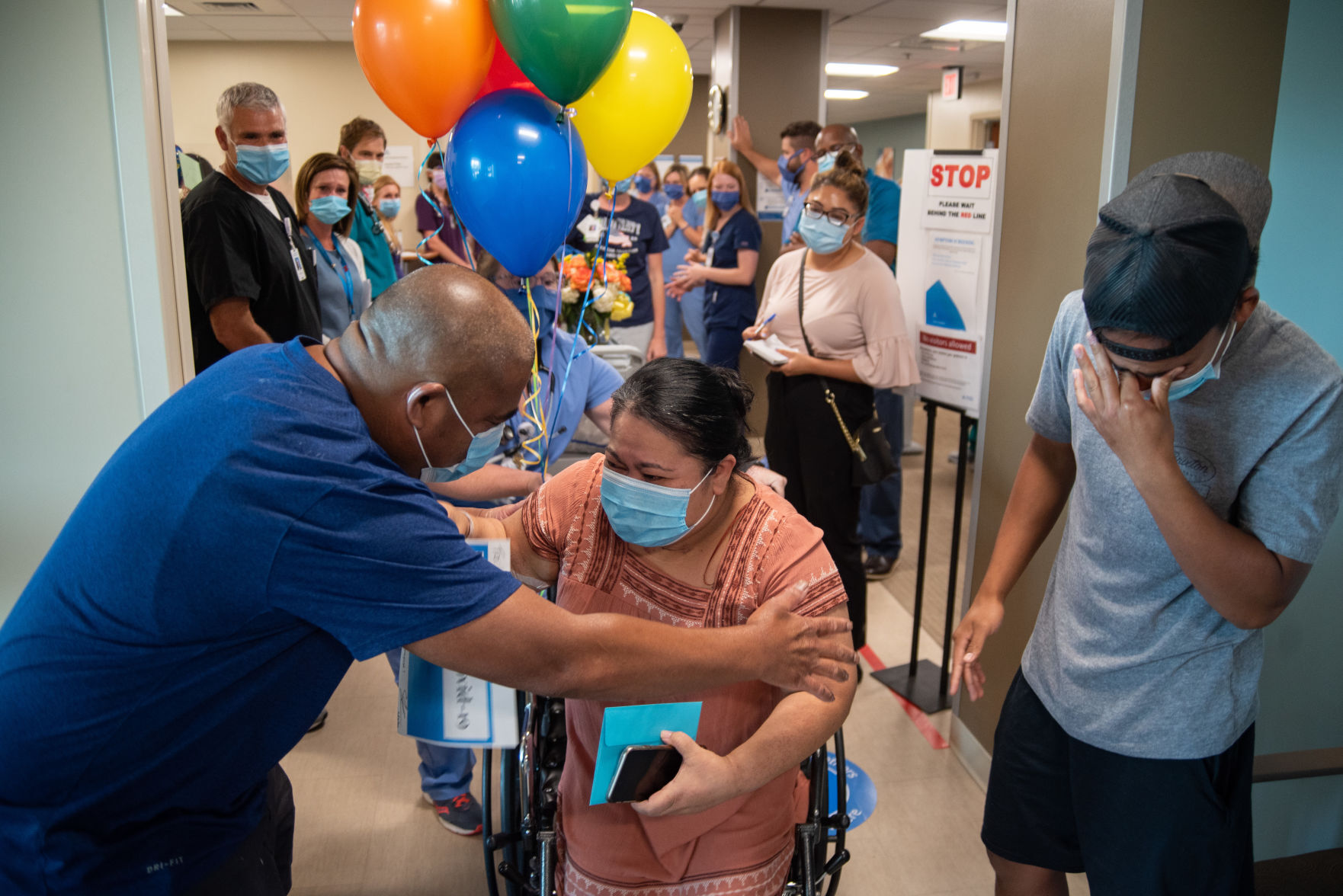 Lisiana Lucios Micky gets out of her wheelchair to hug her husband, Staro Micky, as her son, Jemari Micky, wipes tears from his eyes at Ascension Via Christi Hospital on Thursday.